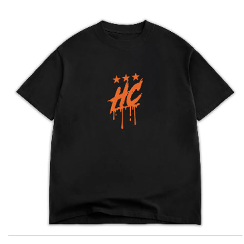 A black t-shirt featuring a bold orange graphic design with the letters HC and three stars above, all appearing to have a dripping effect. The shirt has a casual, relaxed fit, suitable for everyday wear.